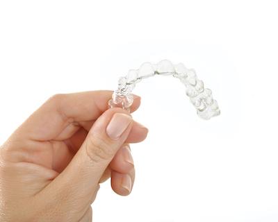 A hand holding an Invisalign tray