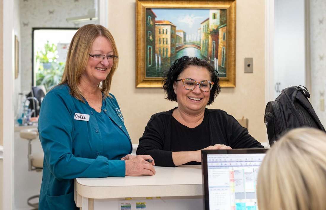 Receptionists speaking to patient at front desk of dentist office in Brandon, FL
